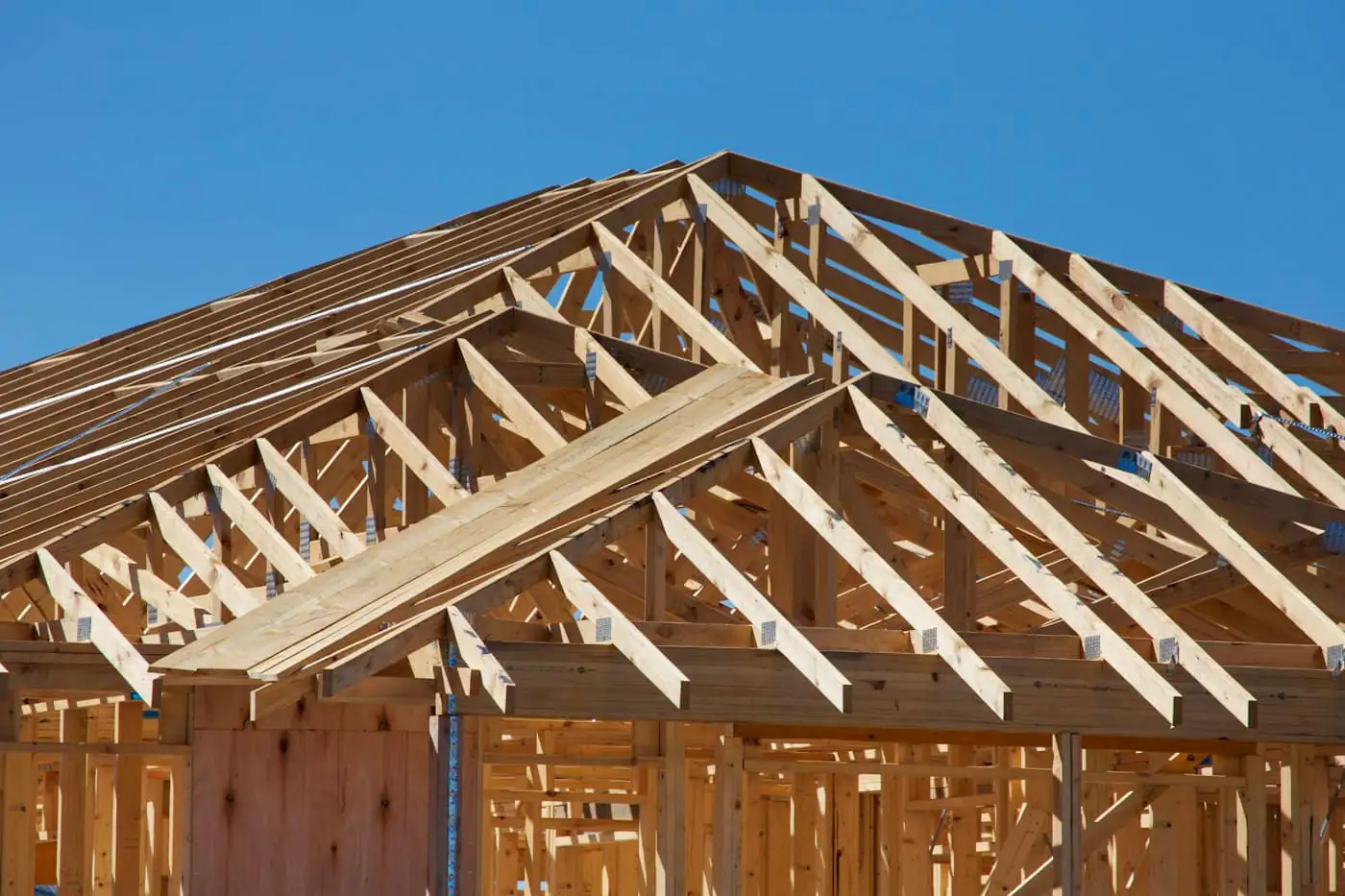 Steel roof trusses with metal roof sheets being fixed on a two-storey house